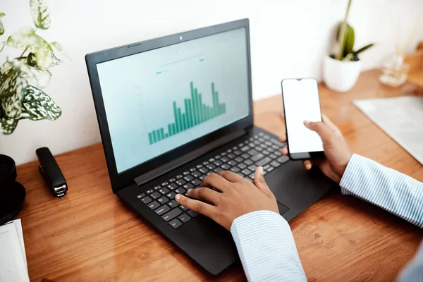 Le succès est à la hausse. Coup de projectile recadré d'une femme d'affaires utilisant un ordinateur portable et un smartphone tout en analysant les données financières à son bureau. — Photo