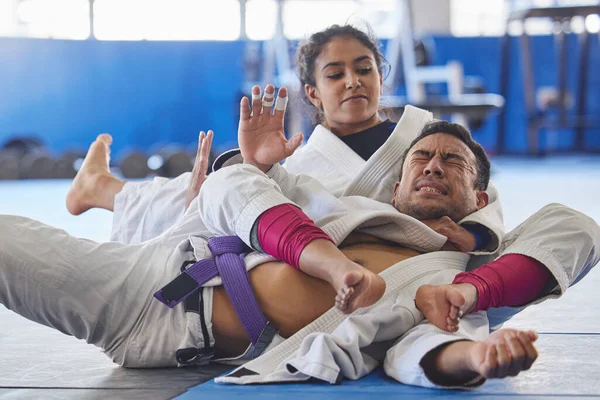 Hon har honom precis där hon vill ha honom. Beskuren bild av två unga kampsporter öva jiu jitsu i gymmet. — Stockfoto