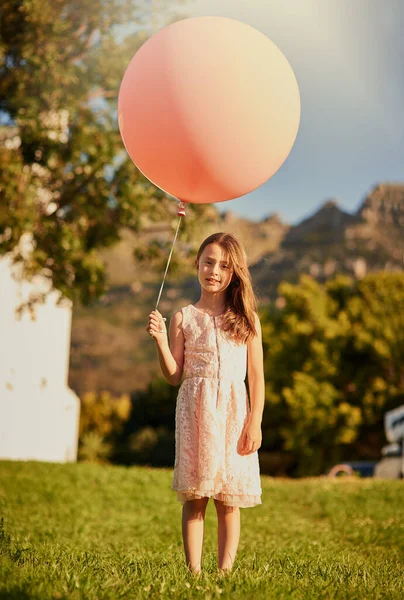 Plus grand et ça m'emmènerait loin. Portrait d'une jolie petite fille tenant un énorme ballon tout en se tenant à l'extérieur. — Photo