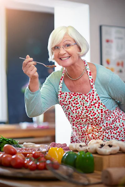 На вкус как домашняя кухня. Снимок пожилой женщины, пробующей еду, которую она готовит. — стоковое фото