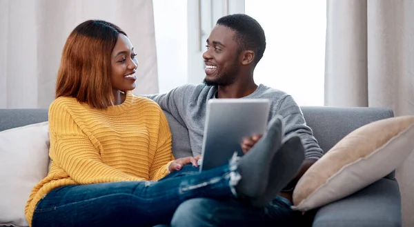 Agora todos sabem o nosso estado de relacionamento. Tiro de um jovem casal usando um tablet digital enquanto relaxa em casa. — Fotografia de Stock