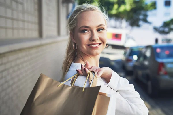 Butikkterapi kler henne. Sprengt bilde av en attraktiv ung kvinne som ser bort tankefullt mens hun oppbevarer handleposer i byen om dagen. – stockfoto