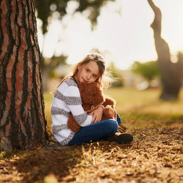 時にはあなたが必要とするすべてはあなたのクマから抱擁です。甘いです女の子抱擁彼女のテディベアながら外でプレイ. — ストック写真