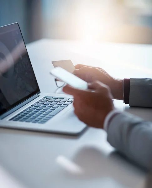 Das Bankwesen könnte nicht effizienter sein. Schnappschuss eines nicht wiederzuerkennenden Geschäftsmannes, der seine Kreditkarte hält, während er einen Laptop an seinem Schreibtisch benutzt. — Stockfoto