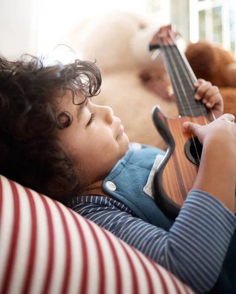 Struikelen naar dromen. Shot van een schattige jonge jongen spelen met een gitaar in zijn slaapkamer thuis. — Stockfoto