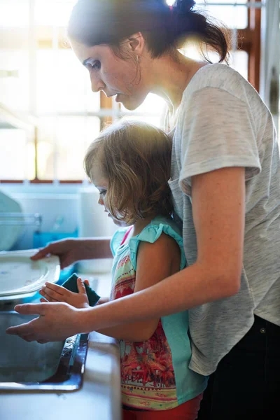 Helpen om de afwas schoon te krijgen. Shot van een moeder en dochter samen afwassen. — Stockfoto