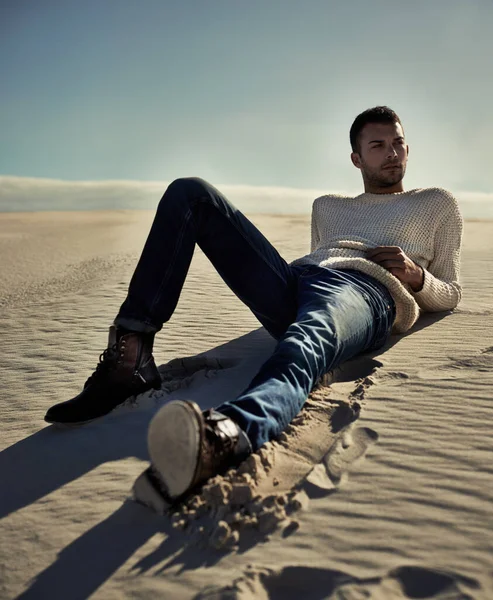 Elegante sin importar dónde esté.... Longitud total de un guapo modelo masculino acostado en la arena del desierto. —  Fotos de Stock