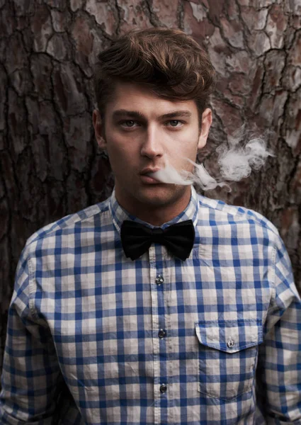 A apanhar ar fresco. Retrato de um jovem hipster fumando na frente de uma árvore. — Fotografia de Stock