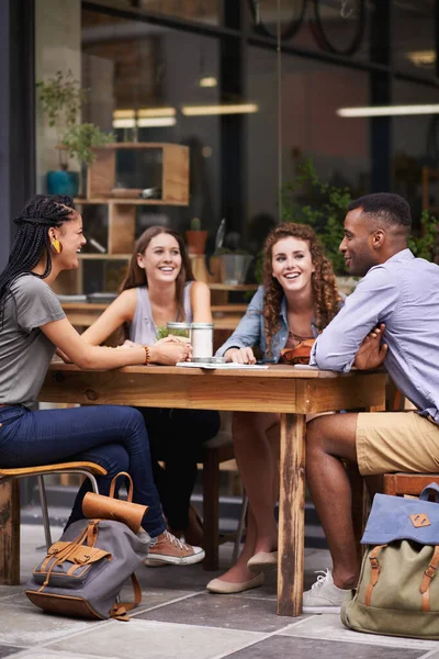 Rien de mieux que la compagnie d'amis. Un groupe de jeunes amis assis dehors dans un café sur le trottoir. — Photo