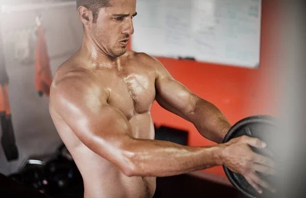 Intensificando su entrenamiento. Recortado tiro de un joven guapo y musculoso haciendo ejercicio con un peso en el gimnasio. — Foto de Stock