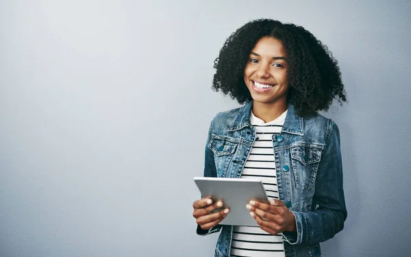 Sie MÜSSEN drahtlos gehen. Studioporträt einer attraktiven jungen Frau mit ihrem digitalen Tablet vor grauem Hintergrund. — Stockfoto