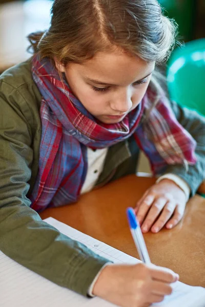 Derslerini bitirmeye çalışıyor. Bir ilkokul öğrencisinin sınıfta ödevlerini yaparken çekilmiş fotoğrafı.. — Stok fotoğraf