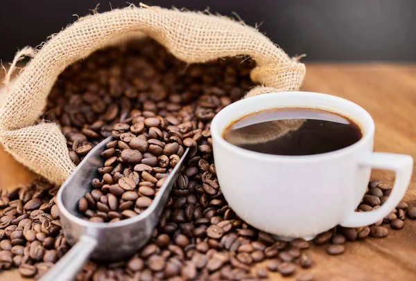 Szeretem a friss és erős kávét. Egy csésze kávébab és egy csésze fekete kávé egy fa asztalon.. — Stock Fotó