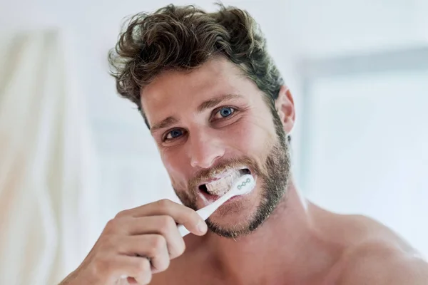 素晴らしい一日のための新鮮な息を先に。自宅で彼の歯を磨くハンサムな若い男の作物のショット. — ストック写真