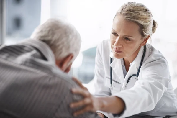 Well get through this. Cropped shot of a mature female doctor working with a senior male patient in her office in the hospital. — Stock Photo, Image