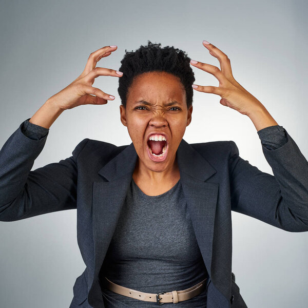 This is madness. Portrait of an angry businesswoman yelling against a grey background.