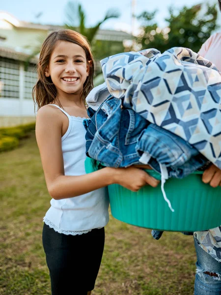 Felice di aiutare la mamma con il bucato. Ritratto di madre e figlia che appendono insieme il bucato fuori. — Foto Stock