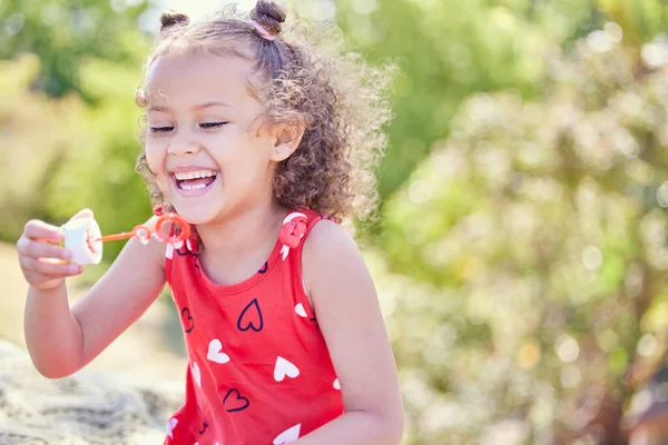 I always get excited about bubbles. Shot of an adorable little girl blowing bubbles at the park. — Stock Photo, Image