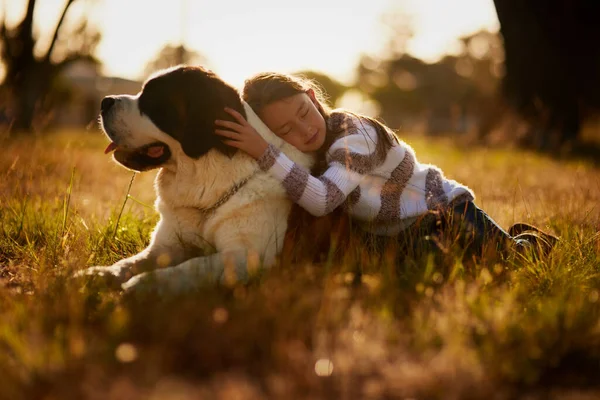 Freunde gibt es in allen Formen und Größen. Aufnahme eines süßen kleinen Mädchens, das mit seinem Hund kuschelt, während sie draußen spielen. — Stockfoto