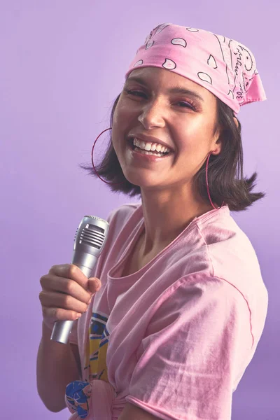 Dis bonjour à la reine du karaoké. Plan studio d'une belle jeune femme chantant avec un microphone sur fond violet. — Photo