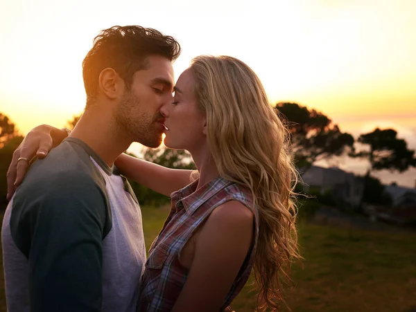 Batidos al atardecer. Foto de una joven pareja cariñosa compartiendo un beso al atardecer. —  Fotos de Stock