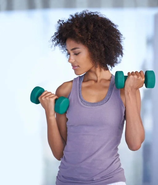 Toning her biceps. Cropped shot of an attractive young woman working out with dumbbells. — Stock Photo, Image