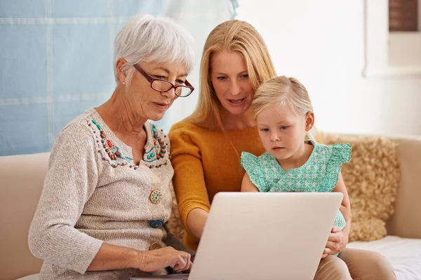Olhando para algumas fotos de família na era digital. Tiro cortado de uma jovem mulher e sua filha sentada com um laptop dentro de casa. — Fotografia de Stock