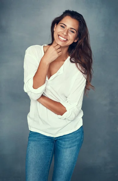 Just keep on smiling. Portrait of a beautiful young woman smiling against a gray background in studio. — Stock Photo, Image