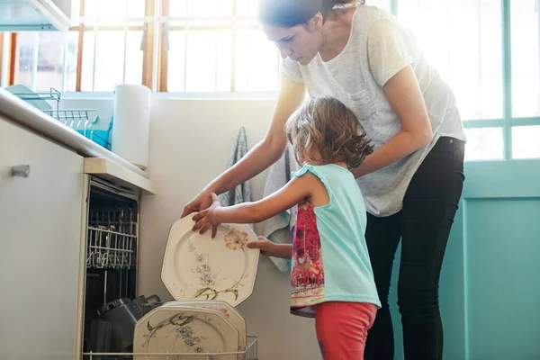 Eén bord tegelijk. Opname van een moeder en dochter druk bezig bij een vaatwasmachine. — Stockfoto