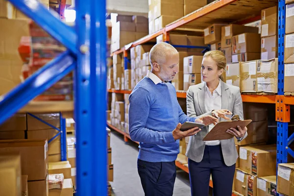 WE always double check our shipments. Shot of a man and woman inspecting inventory in a large distribution warehouse. — Stock Photo, Image