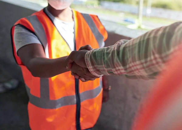 Laten we samenwerken om nog beter te bouwen. Schot van twee bouwers die elkaar de hand schudden op een bouwplaats. — Stockfoto