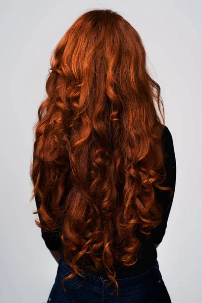 Μεγάλωσε το, δυνάμωσέ το. Στούντιο πλάνο μιας νεαρής γυναίκας με όμορφα κόκκινα μαλλιά ποζάρουν σε γκρι φόντο. — Φωτογραφία Αρχείου