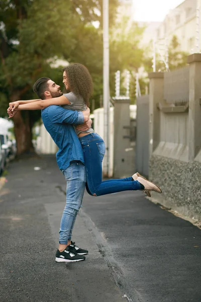 He cant believe his luck. Shot of a young man lifting his girlfriend while standing outside. — Stock Photo, Image
