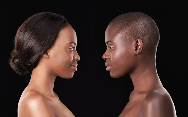 Idealne profile. Dwie piękne afrykańskie kobiety stojące twarzą w twarz na czarnym tle. — Zdjęcie stockowe
