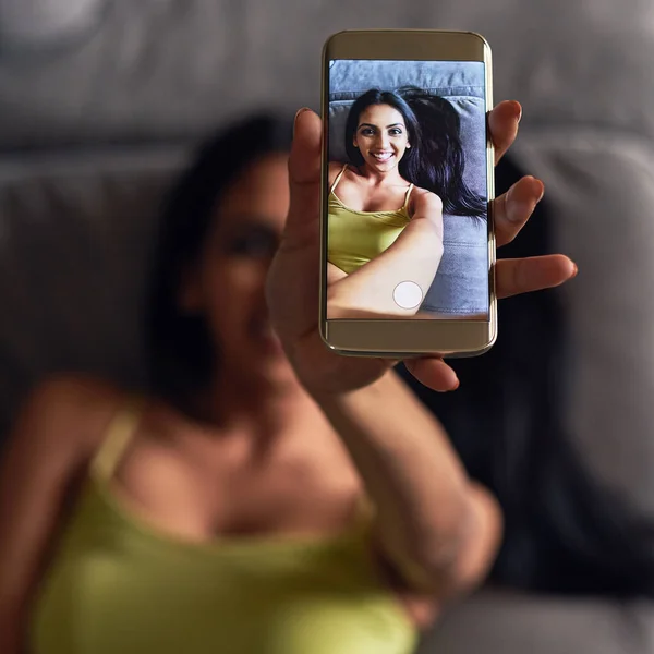 Schnappt ein Selfie auf dem Sofa. Hochwinkelaufnahme einer attraktiven jungen Frau, die ein Selfie macht, während sie zu Hause auf ihrem Sofa liegt. — Stockfoto