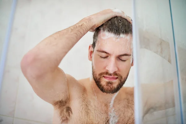 Begin uw dag met een verfrissende noot. Gehakte foto van een knappe jongeman die thuis een douche heeft. — Stockfoto