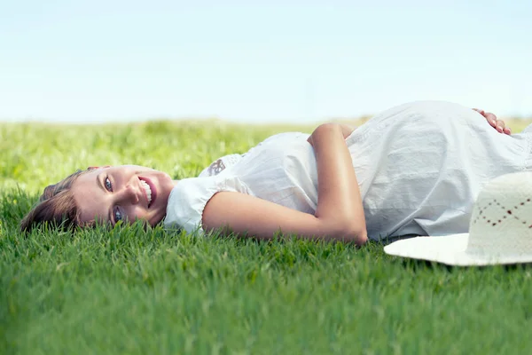 Conta alla rovescia i giorni. Una bella donna sdraiata sull'erba all'aperto e rilassante sotto il sole. — Foto Stock