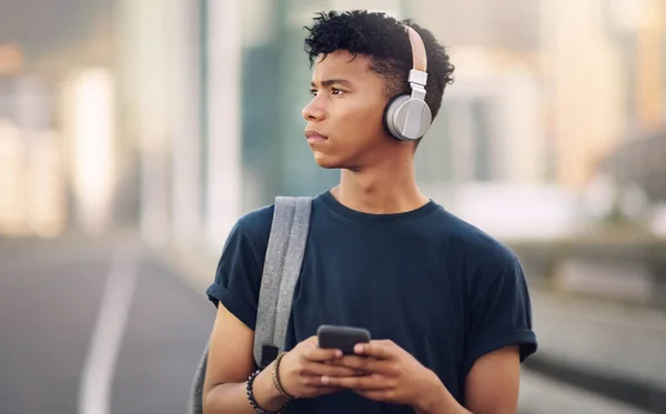 A zene az élet. Vágott felvétel egy jóképű fiatalemberről, aki az utcán ébred, és zenét hallgat a mobiljáról.. — Stock Fotó