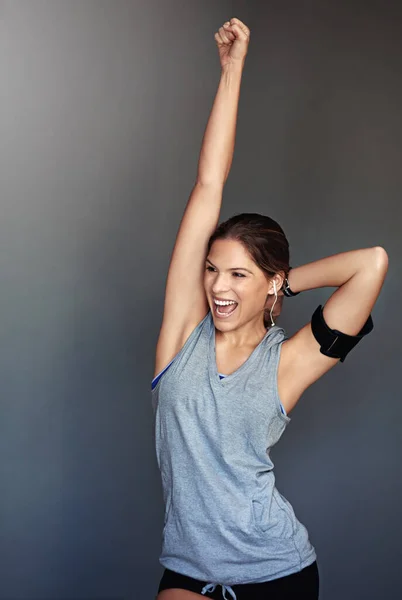 Lucha por el progreso, no por la perfección. Foto de una joven deportista celebrando una victoria sobre un fondo gris. —  Fotos de Stock