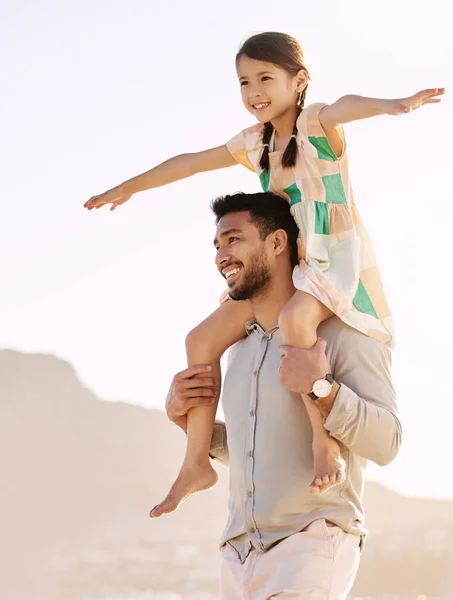 Rider högt på pappas axlar. Beskuren bild av en stilig ung man som bär sin dotter på sina axlar på stranden. — Stockfoto