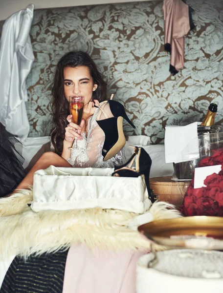 Lyxen i livet. Porträtt av en vacker ung kvinna som kopplar av på sängen och omges av presenter medan hon dricker champagne. — Stockfoto