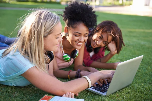 Ajudar-nos mutuamente numa missão difícil. Três jovens estudantes deitados na grama em um parque e usando um laptop. — Fotografia de Stock