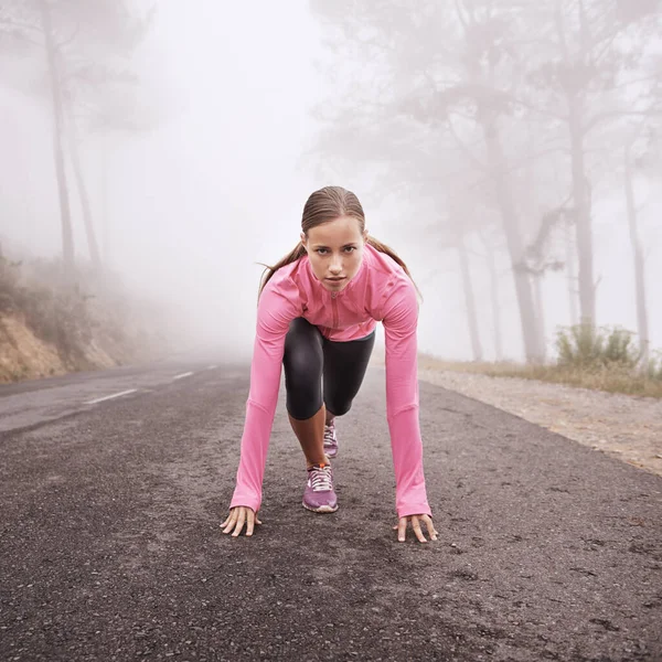 Psiquiátrica para fugir. Tiro de uma jovem corredora prestes a iniciar uma sessão de treinamento em uma manhã enevoada. — Fotografia de Stock
