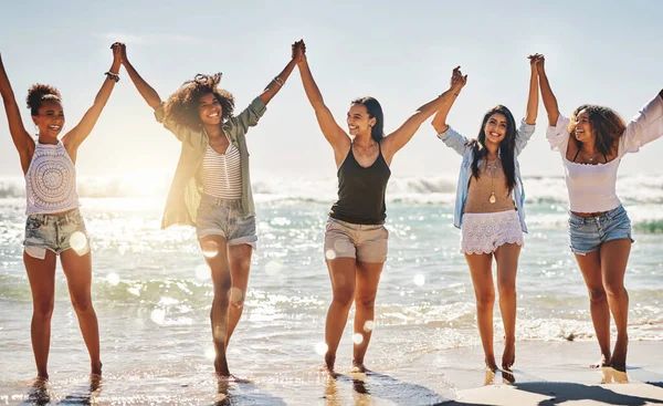 Sommeren ble skapt for slike dager. Skutt av en gruppe lystige venner som holdt hverandre i hånden på stranden. – stockfoto