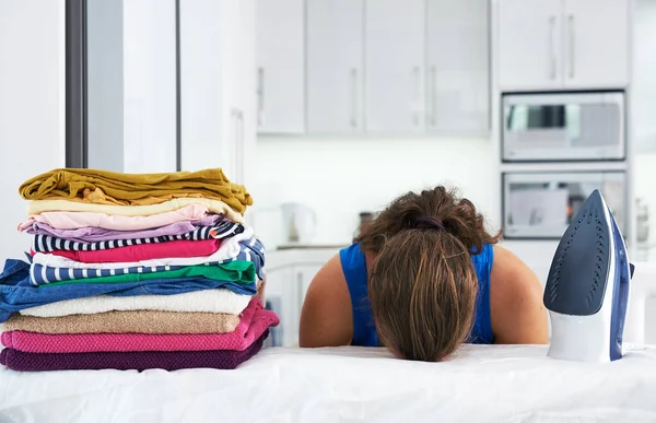 Shes run out of steam. Shot of a young woman with her head down on an ironing board. — Stock Photo, Image