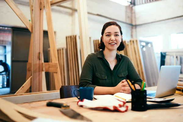 Recortamos madera en hermosas piezas para su hogar. Foto recortada de una mujer carpintera sentada en su escritorio en un taller. — Foto de Stock