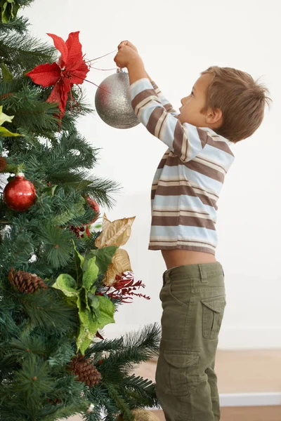 Цього року Хесус прикрашає дерево самостійно. Постріл хлопчика, який прикрашає ялинку сам . — стокове фото