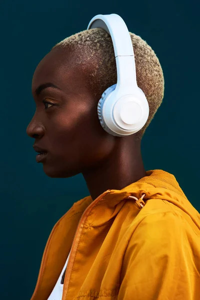 Vamos começar esta sessão de treino. Tiro recortado de uma jovem esportista atraente sozinha contra um fundo escuro e ouvindo música através de fones de ouvido. — Fotografia de Stock