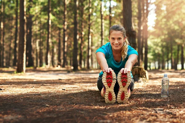 Estirar es la parte más importante. Tiro de una joven deportista haciendo ejercicio de estiramiento mientras está en la naturaleza. — Foto de Stock