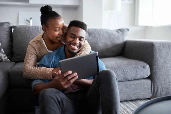 Teilen in einer ganz besonderen Verbindung. Aufnahme eines jungen Paares, das gemeinsam ein digitales Tablet benutzt, während es sich zu Hause entspannt. — Stockfoto